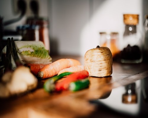 Rustic kitchen countertop with colorful fresh vegetables and a glass bottle of clean water